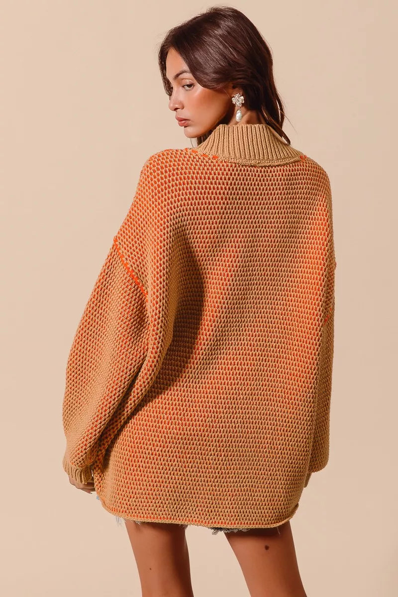 Woman wearing a pumpkin orange oversized knitted sweater against a beige background